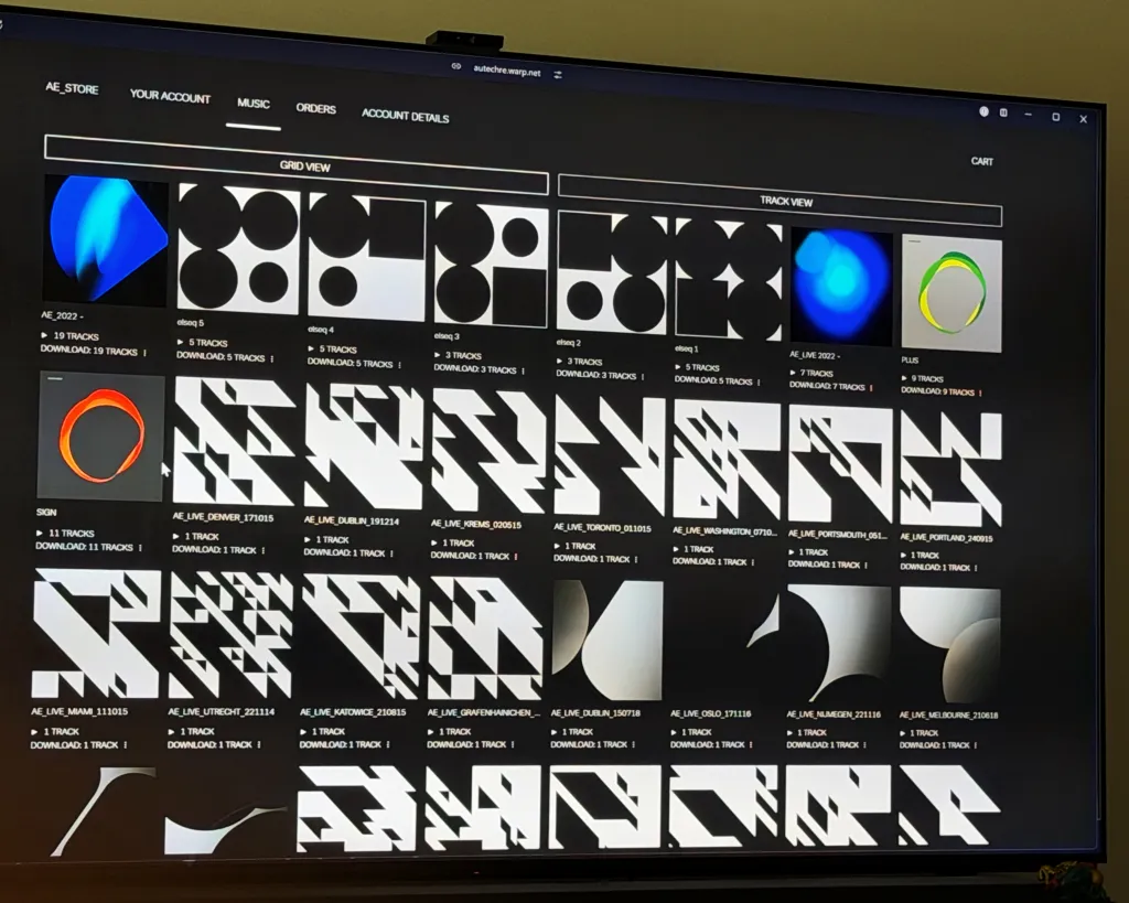 The Autechre AE_STORE (autechre.warp.net) music library in grid view on a TV screen, its tiles showing AE_2022, the elseq series, AE_LIVE 2022, PLUS, SIGN, and a grid of individual AE_LIVE show downloads — Denver, Dublin, Krems, Toronto, Washington, Portsmouth, Portland, Miami, Utrecht, Katowice, Oslo, Nijmegen, Melbourne and more